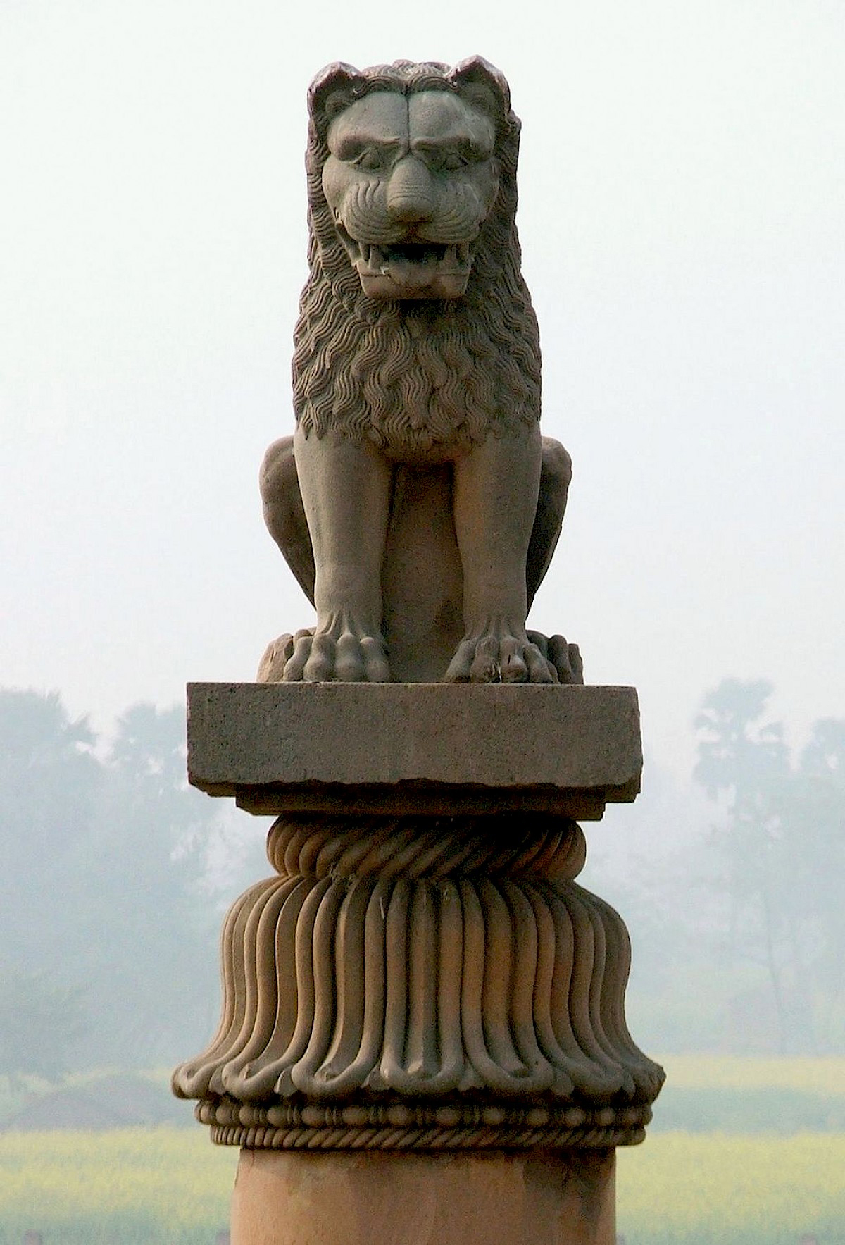 A stone statue of a lion sitting on its hind quarters atop a pillar.